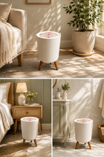 Load image into Gallery viewer, A collage of three interior scenes showing a small cylindrical white ribbed side table with tapered wooden legs and a pink floral patterned top, styled in a bedroom, living room, and bathroom setting.