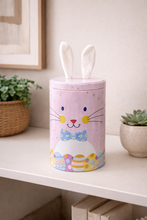 Load image into Gallery viewer, Bunny themed pastel decorative storage canister with fabric ears on shelf