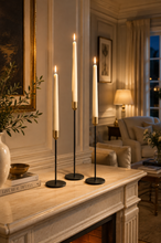 Load image into Gallery viewer, Black and gold metal candle holder set with battery-powered LED taper candles in a warm living room