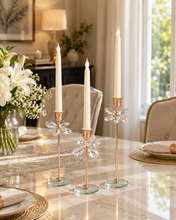 Load image into Gallery viewer, Crystal Bloom 3-piece rose gold candle holder set with crystal flower accents and glass bases on marble dining table