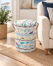 Load image into Gallery viewer, Ocean-patterned cylindrical stool with a cushioned top and rope handles beside a cream armchair.
