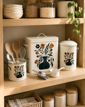 Load image into Gallery viewer, 4-piece floral metal kitchen storage set with cream finish and botanical design including 12L storage bin, 8L canister, utensil holder and scoop on kitchen counter.