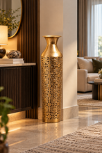 Load image into Gallery viewer, Tall golden filigree floor vase beside a dark wooden console in a modern entryway.