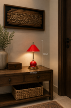 Load image into Gallery viewer, A red table lamp with a conical red shade, gold-toned stem, and round red base sits on a dark wood console table in a warmly lit interior. White measurement lines and text indicate the lamp's height of 13 inches and diameter of 6 inches.
