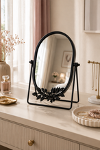 Load image into Gallery viewer, Black oval botanical tabletop vanity mirror with decorative metal leaf design on vanity table – MetaphorBD
