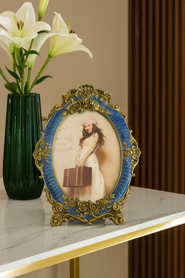 Royal blue vintage oval photo frame with floral gold accents on marble console