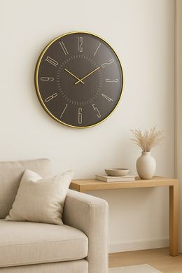 Large round matte black wall clock with gold numerals in a minimalist living room