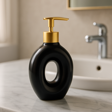 Load image into Gallery viewer, White ceramic soap dispenser with gold pump on bathroom counter from MetaphorBD.
