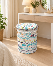 Load image into Gallery viewer, Ocean-inspired upholstered stool with a padded round top and rope handles beside a dressing table.
