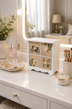 Load image into Gallery viewer, White and wood-tone 4-drawer decorative mini organizer cabinet with botanical, bicycle and LOVE designs on console table.
