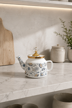Load image into Gallery viewer, Floral enamel tea kettle in white with blue-grey floral pattern, gold-tone detailing and crystal-style accents, available in 1-liter and 2.4-liter capacities.
