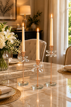 Load image into Gallery viewer, Crystal Bloom 3-piece rose gold candle holder set with lit taper candles on marble dining table
