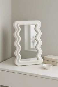 Wavy white plastic frame mirror on console table – modern minimalist home décor