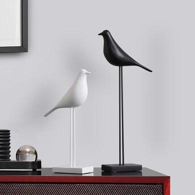 Black and white bird figurines on stands used as minimalist Nordic decor on red console table