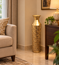 Load image into Gallery viewer, Golden filigree metal floor vase with a flared neck, styled beside a sofa and wooden console.
